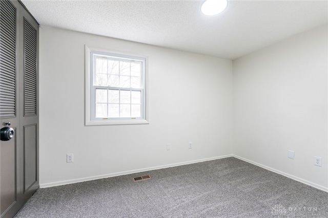 empty room with carpet floors and a textured ceiling