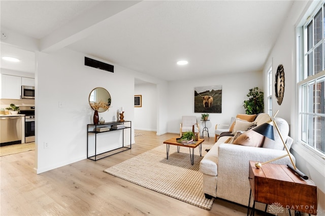 living room featuring beam ceiling and light wood-type flooring