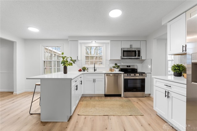 kitchen with stainless steel appliances, white cabinetry, a breakfast bar, and kitchen peninsula