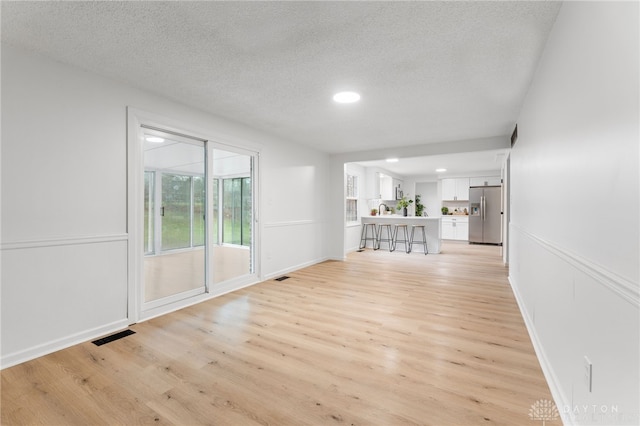 empty room with light hardwood / wood-style flooring and a textured ceiling