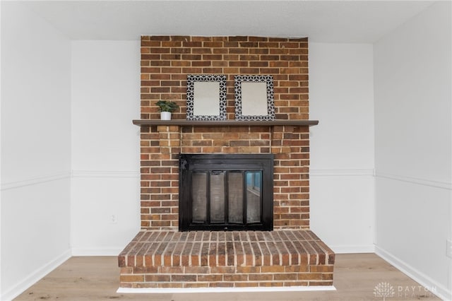 interior details featuring a brick fireplace and hardwood / wood-style floors