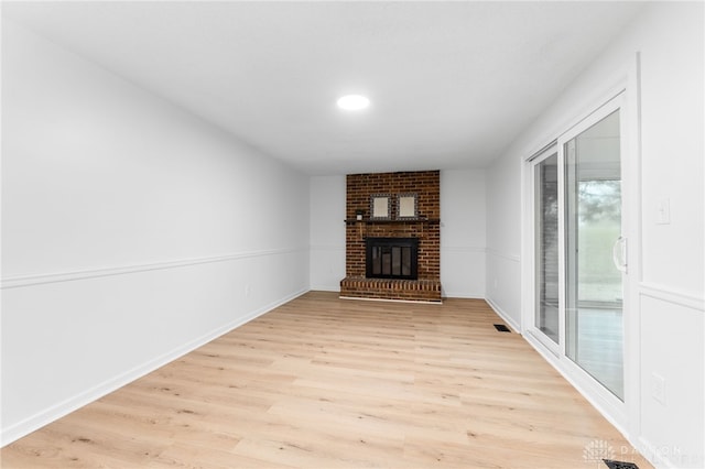 unfurnished living room featuring a brick fireplace and light hardwood / wood-style flooring