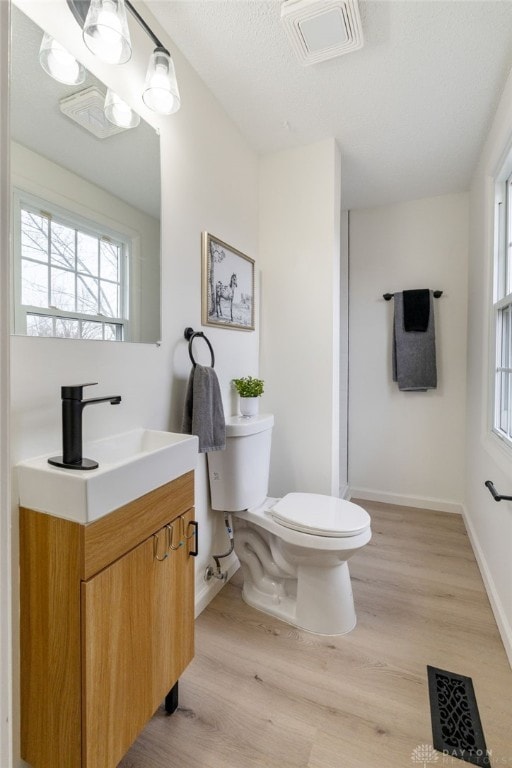 bathroom with vanity, a textured ceiling, wood-type flooring, and toilet