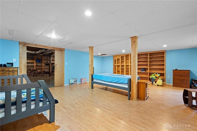 bedroom with wood-type flooring and a drop ceiling