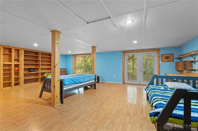 bedroom with french doors, wood-type flooring, access to exterior, and multiple windows