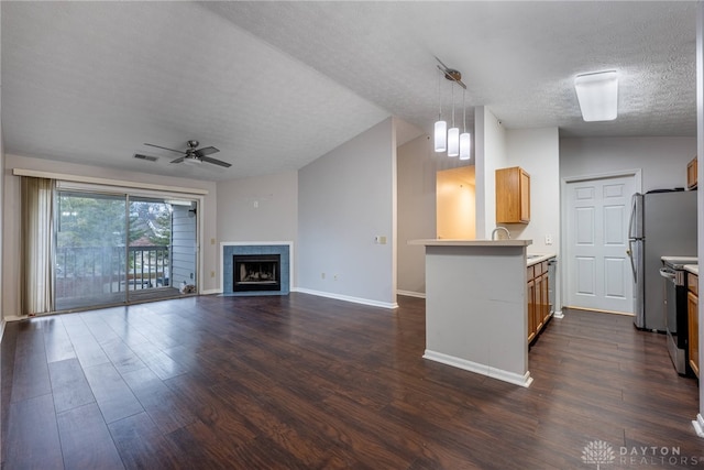 unfurnished living room with ceiling fan, lofted ceiling, dark hardwood / wood-style flooring, and a textured ceiling