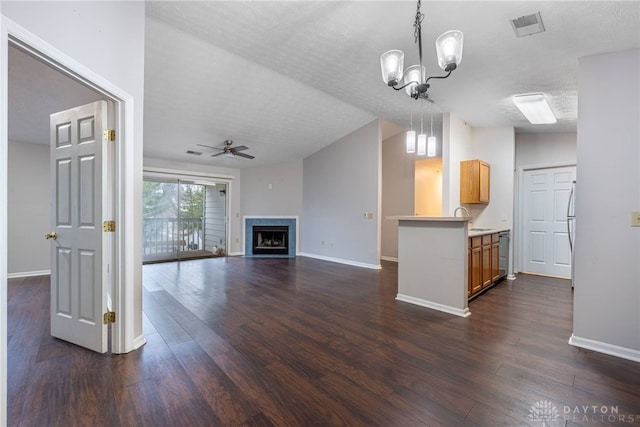 unfurnished living room with lofted ceiling, dark hardwood / wood-style floors, ceiling fan with notable chandelier, and a textured ceiling