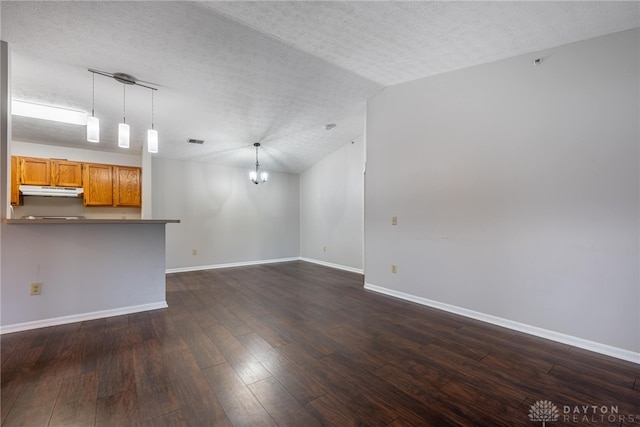 unfurnished living room with dark wood-type flooring, lofted ceiling, an inviting chandelier, and a textured ceiling