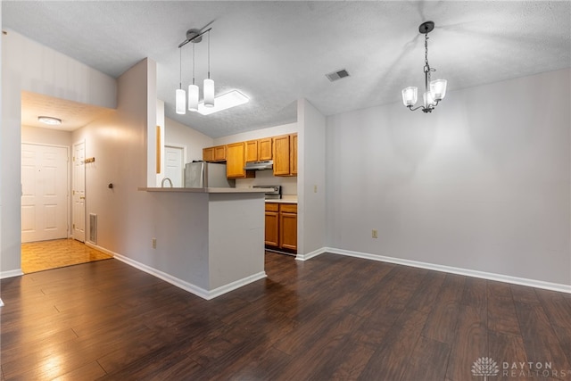 kitchen with dark wood-type flooring, lofted ceiling, hanging light fixtures, stainless steel fridge, and kitchen peninsula