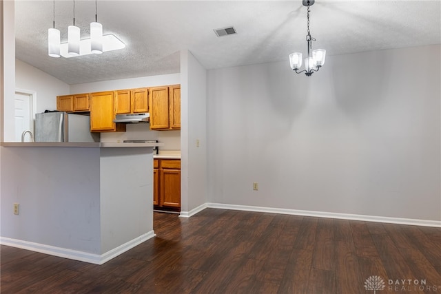 kitchen featuring stainless steel refrigerator, dark hardwood / wood-style floors, hanging light fixtures, and a textured ceiling