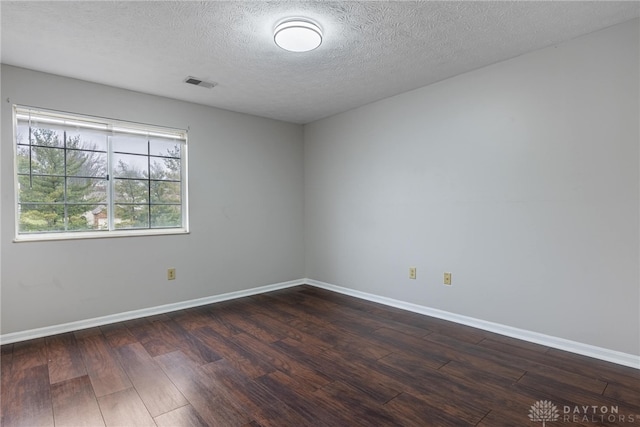 spare room featuring dark hardwood / wood-style flooring and a textured ceiling