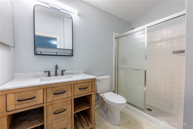 bathroom featuring vanity, a textured ceiling, a shower with door, and toilet