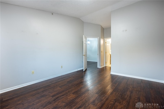 empty room featuring lofted ceiling and dark hardwood / wood-style flooring