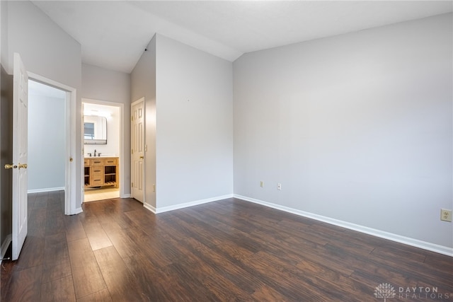 unfurnished bedroom featuring lofted ceiling, dark hardwood / wood-style flooring, and ensuite bathroom