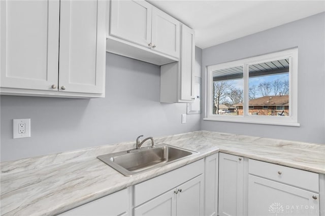 kitchen featuring light stone countertops, sink, and white cabinets