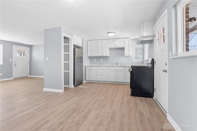 kitchen with range with gas cooktop, white cabinetry, sink, stainless steel fridge, and light hardwood / wood-style flooring