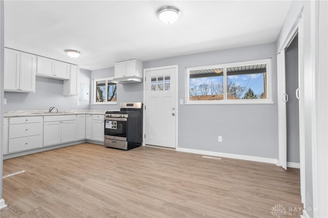 kitchen with white cabinetry, stainless steel gas range oven, a healthy amount of sunlight, and light wood-type flooring