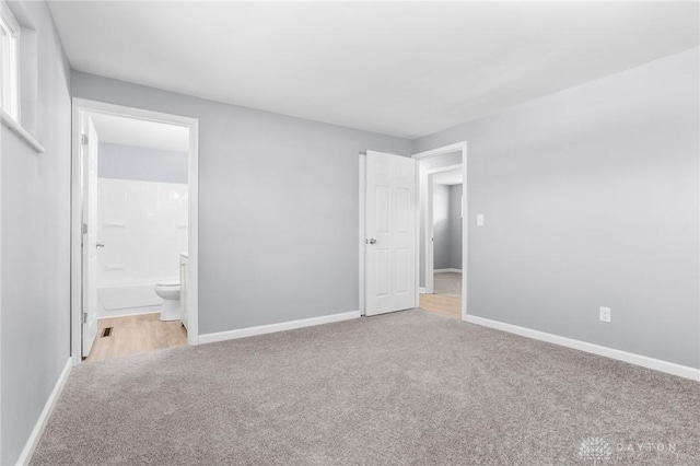 unfurnished bedroom featuring ensuite bathroom and light carpet