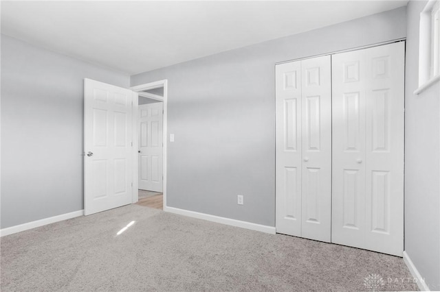 unfurnished bedroom featuring light colored carpet and a closet