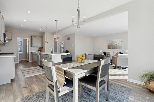 dining space featuring sink, a notable chandelier, and light hardwood / wood-style floors