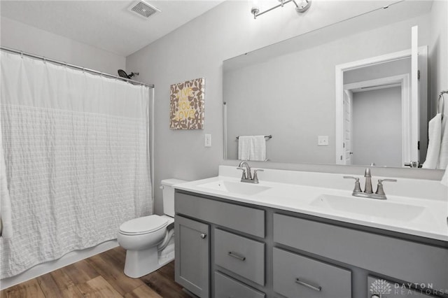 full bathroom featuring vanity, hardwood / wood-style floors, shower / bath combo, and toilet