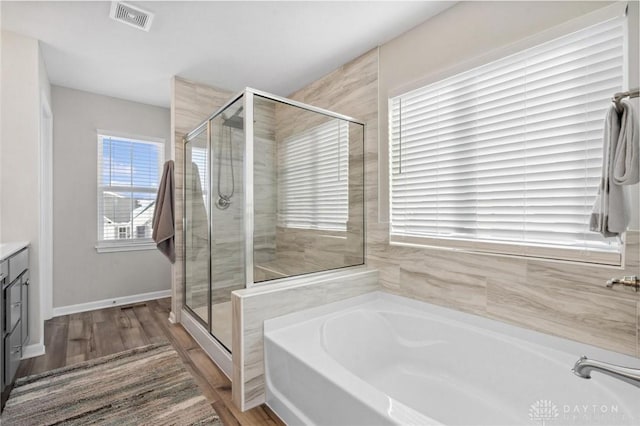 bathroom featuring hardwood / wood-style flooring, vanity, and plus walk in shower