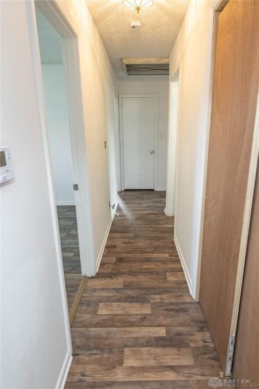 corridor featuring dark wood-type flooring and a textured ceiling