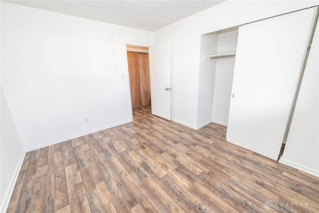 unfurnished bedroom with dark wood-type flooring, a textured ceiling, and a closet