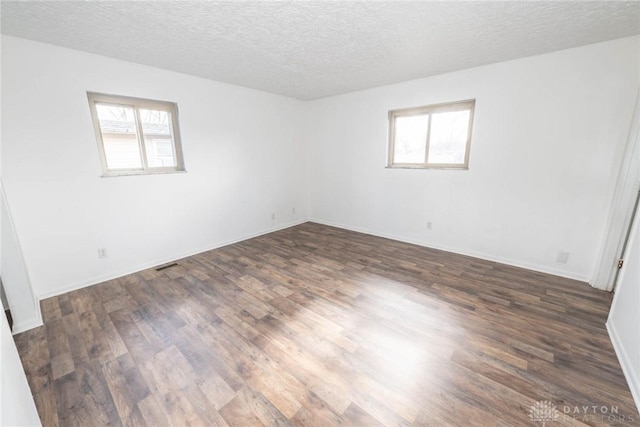 unfurnished room featuring a wealth of natural light, a textured ceiling, and dark hardwood / wood-style flooring