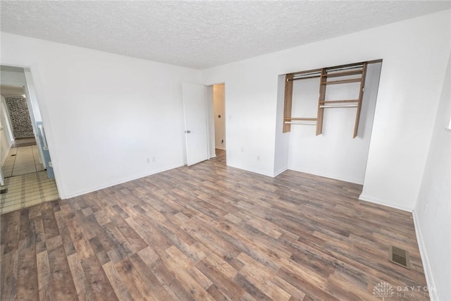 unfurnished bedroom with a closet, dark hardwood / wood-style floors, and a textured ceiling