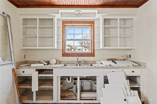 interior space with wood ceiling, light stone countertops, and sink