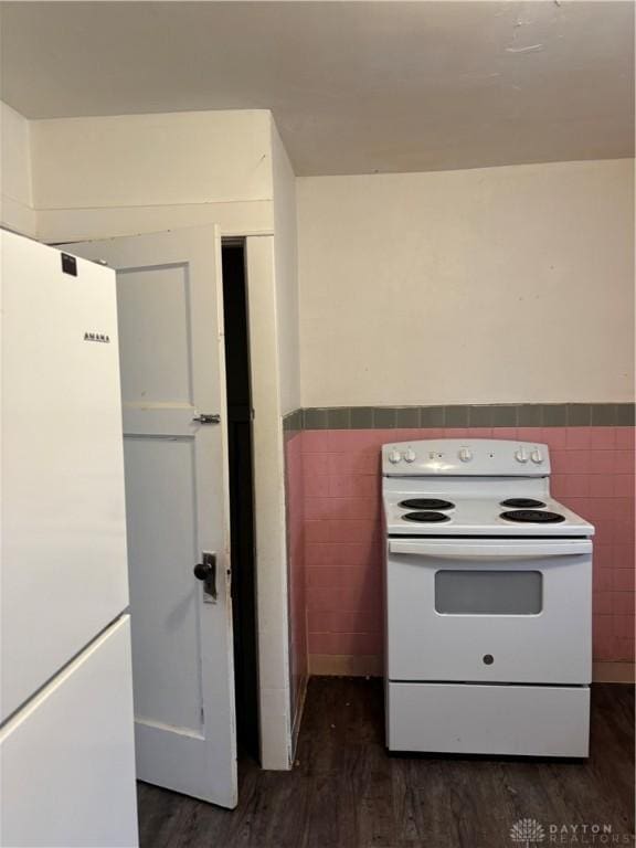 kitchen with dark wood-type flooring, white appliances, and tile walls