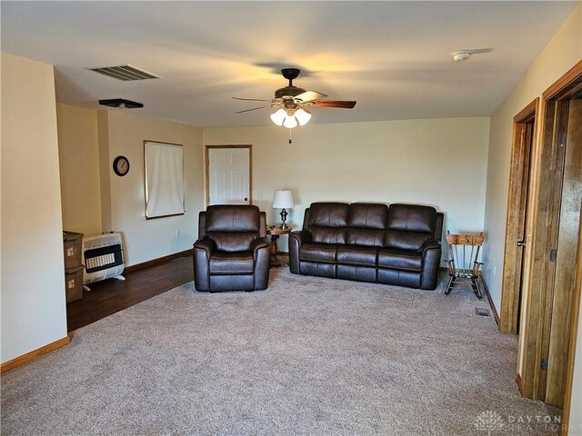 living room with heating unit, dark carpet, and ceiling fan