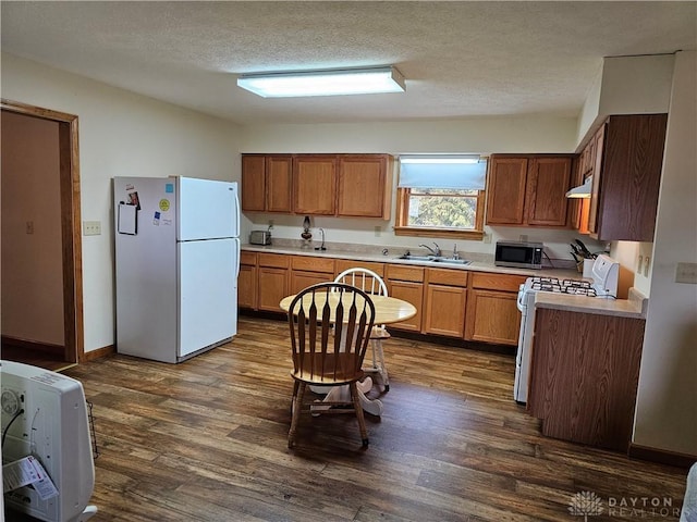 kitchen featuring dark hardwood / wood-style flooring, sink, white appliances, and a textured ceiling