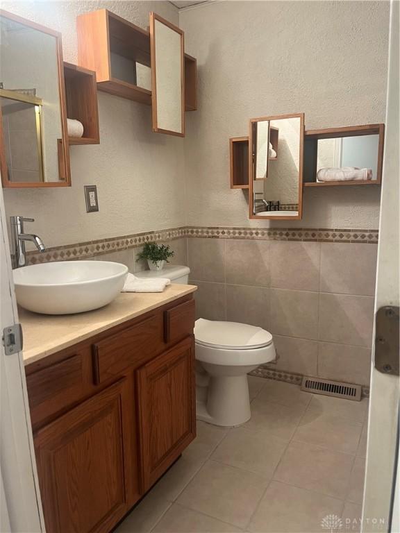 bathroom featuring vanity, tile walls, tile patterned floors, and toilet