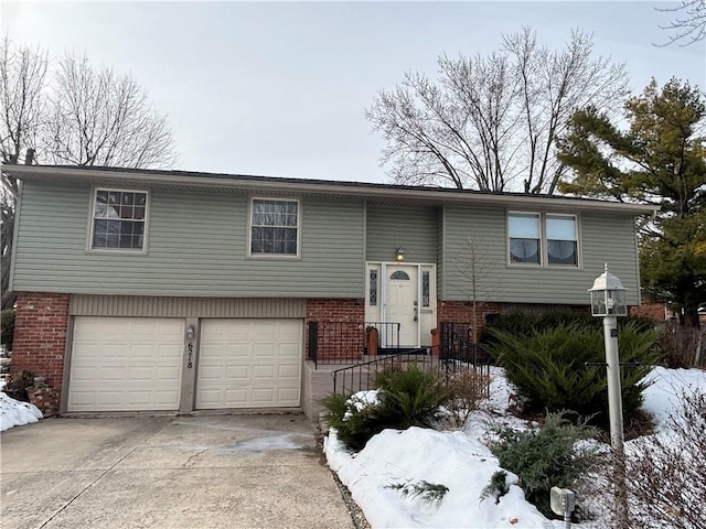 raised ranch with a garage, concrete driveway, and brick siding