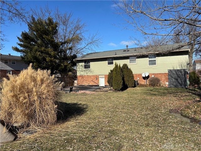 rear view of property with brick siding, a patio area, and a yard