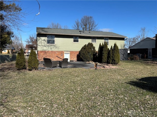 rear view of property featuring a yard, brick siding, a patio area, and fence