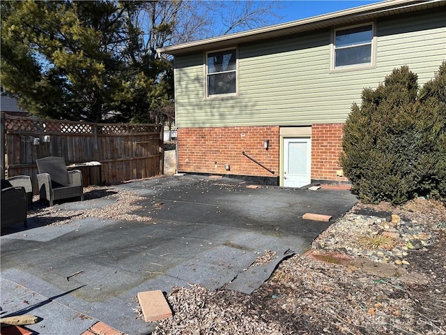 exterior space with brick siding, fence, and a patio