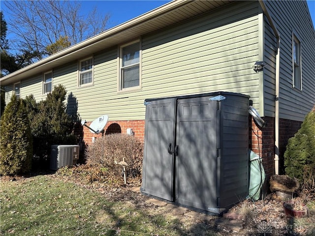 view of side of property featuring central AC unit and brick siding