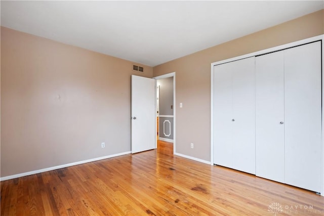 unfurnished bedroom featuring a closet, visible vents, light wood-style flooring, and baseboards