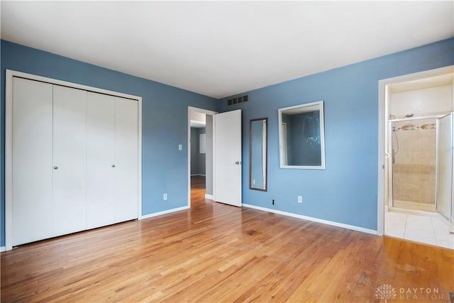 unfurnished bedroom featuring light wood finished floors, baseboards, visible vents, and a closet