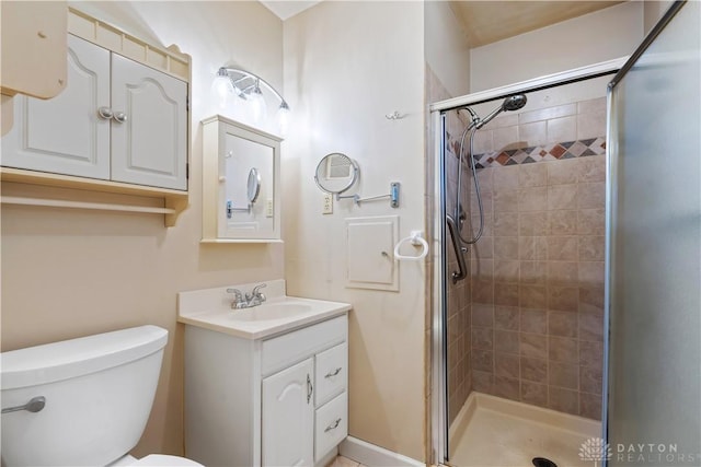 bathroom featuring toilet, a shower stall, and vanity