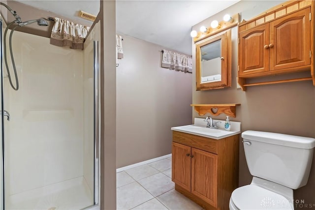 bathroom with toilet, vanity, a shower stall, baseboards, and tile patterned floors