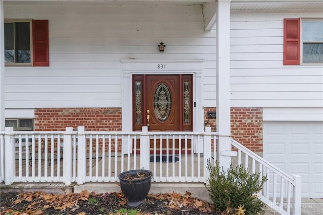 doorway to property featuring a garage and brick siding