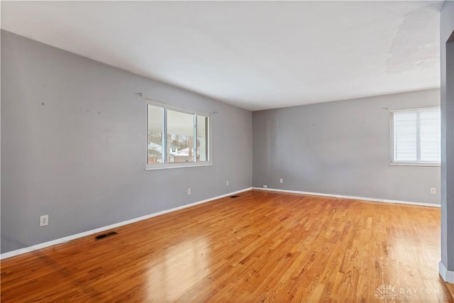 spare room with light wood finished floors, baseboards, and visible vents