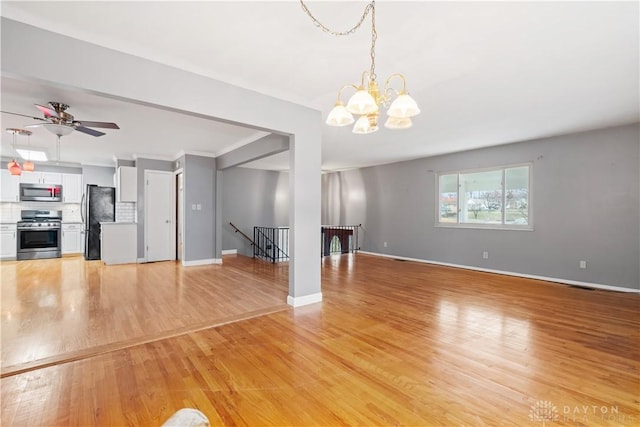 unfurnished living room featuring baseboards, ceiling fan with notable chandelier, visible vents, and light wood-style floors