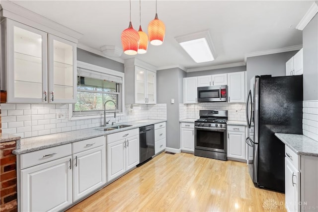 kitchen featuring light wood-style flooring, appliances with stainless steel finishes, ornamental molding, white cabinets, and a sink