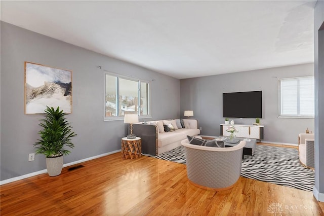 living area featuring visible vents, baseboards, and wood finished floors