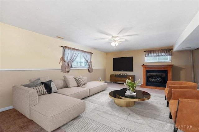 living room with carpet, visible vents, a glass covered fireplace, ceiling fan, and baseboards